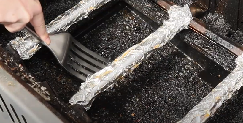 Spatula scraping built-up debris on the bottom of the grill