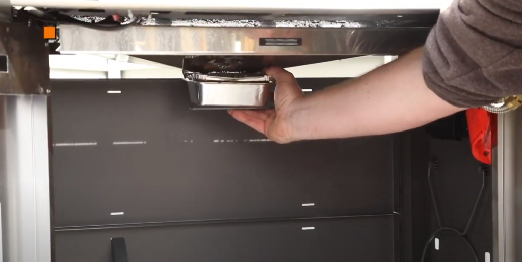 Removing the grease tray from the grill